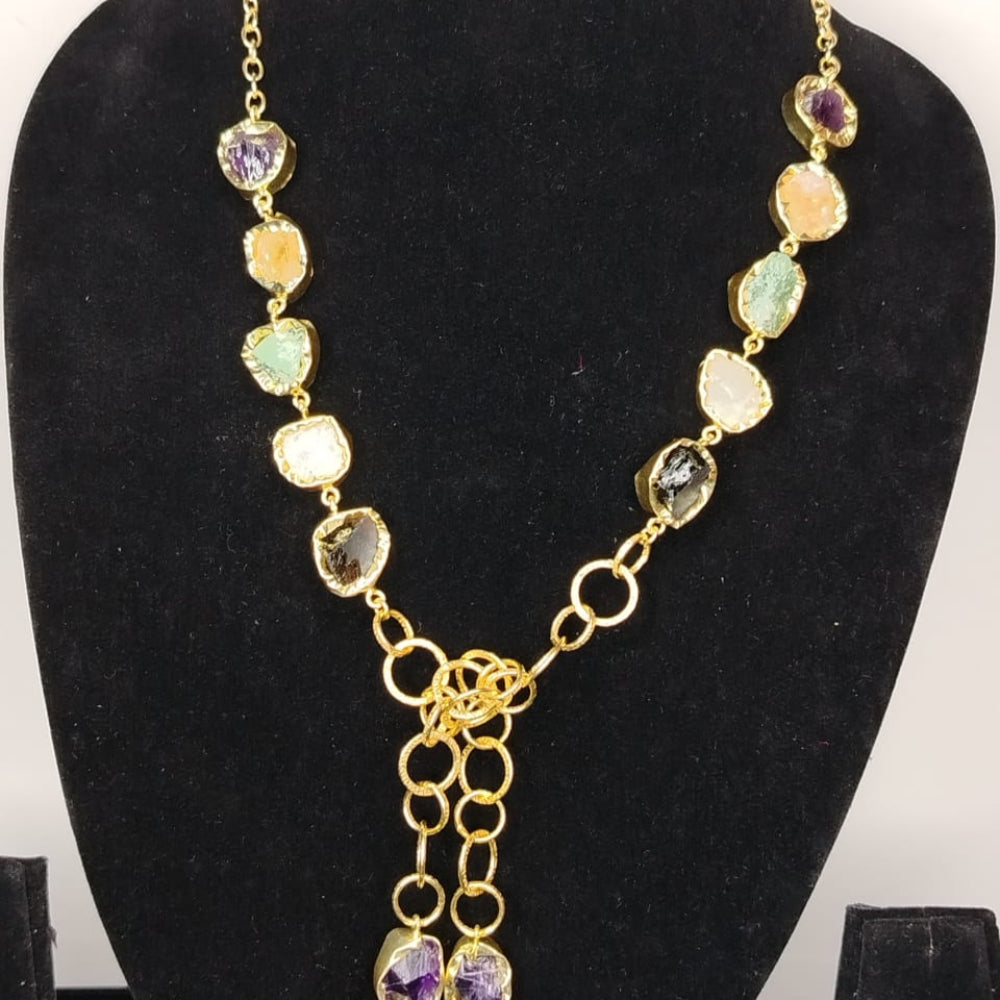 Necklace with multicolored gemstones and gold chain on a black stand
