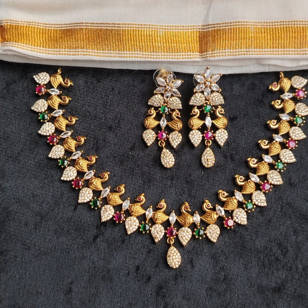 Gold necklace with gemstones on a dark background next to a saree with yellow and white pattern.