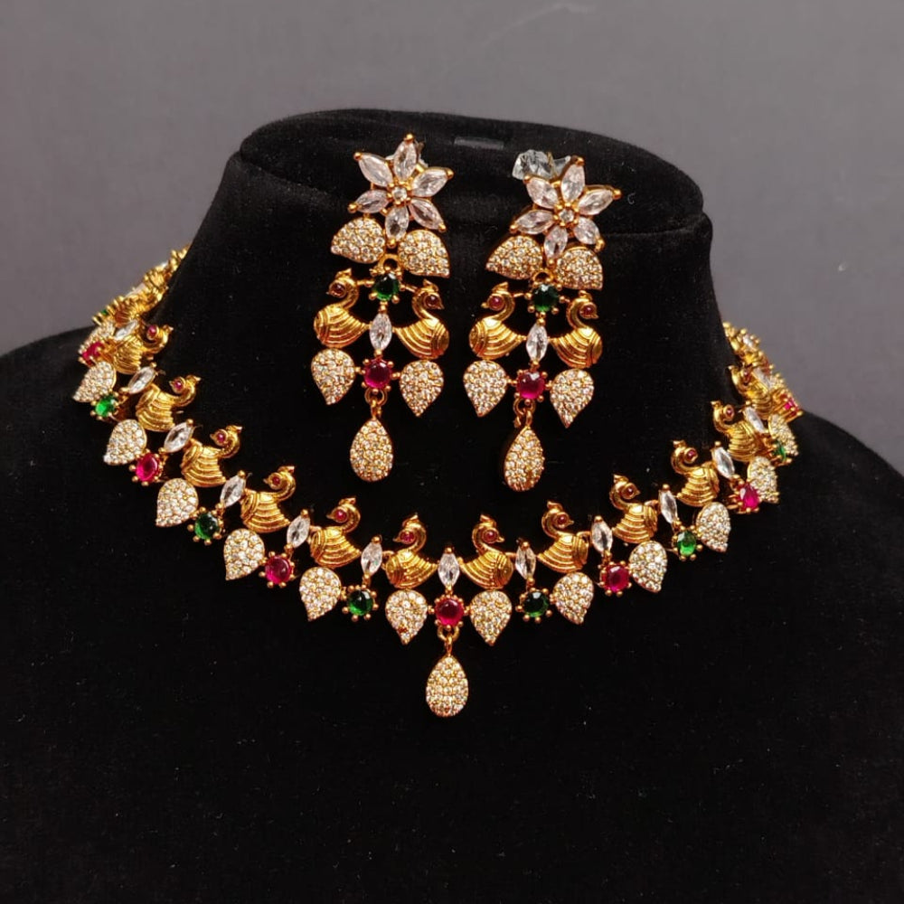 Gold jewelry set with floral designs on a black stand against a gray background