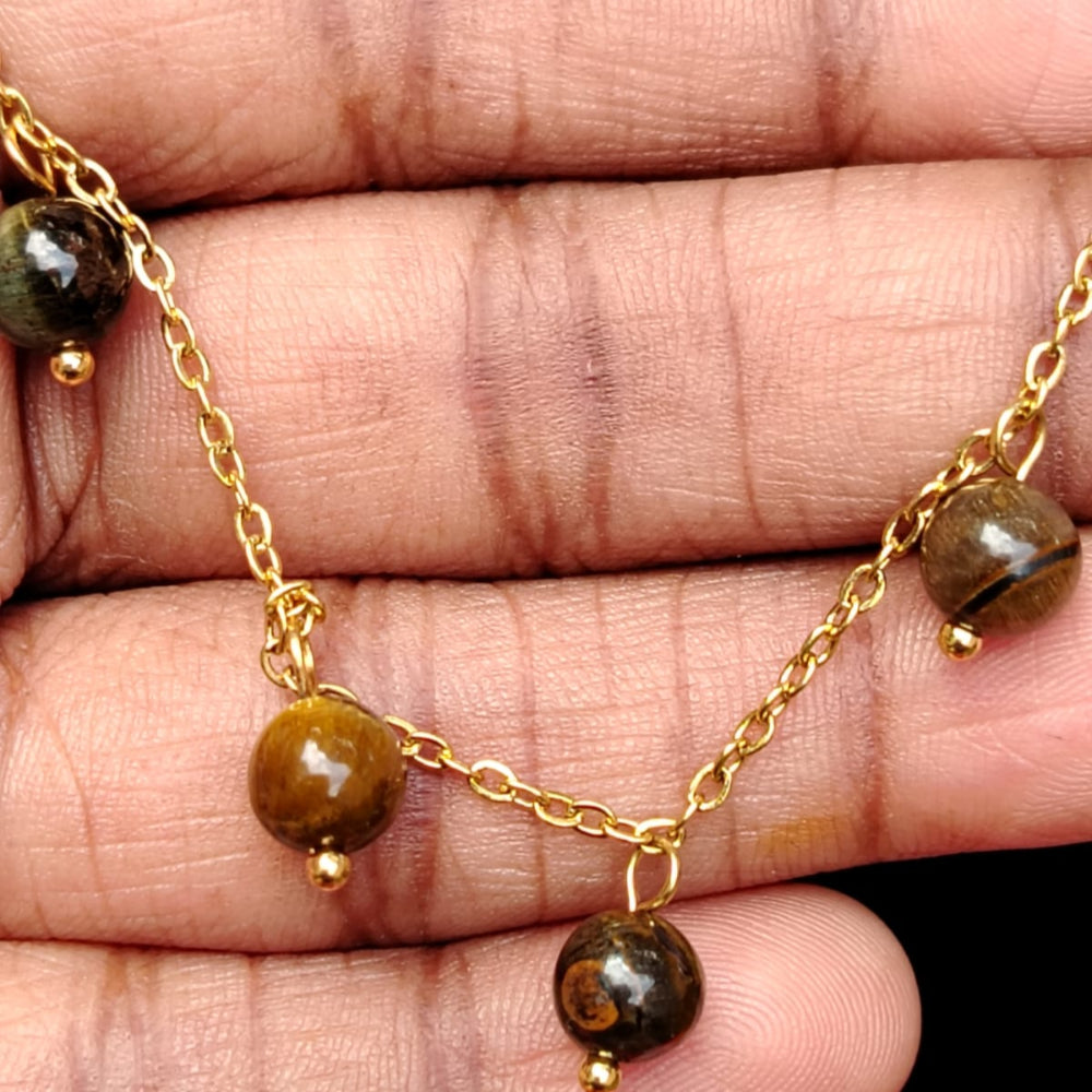 Gold necklace with brown beads on a hand