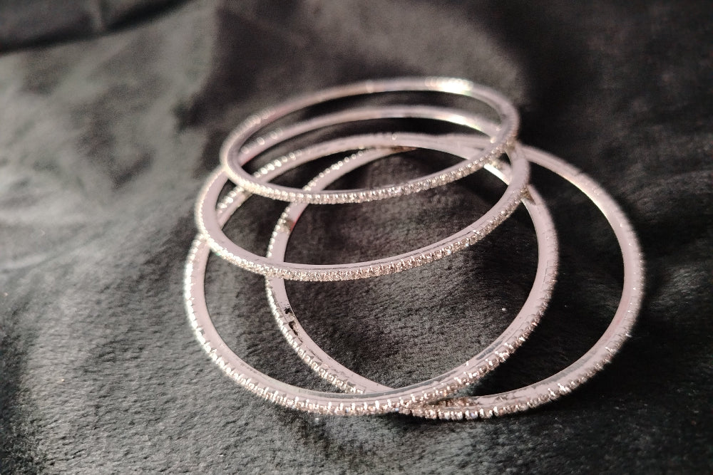 4 Sleek AD Bangles Lying Scattered on Black Fabric