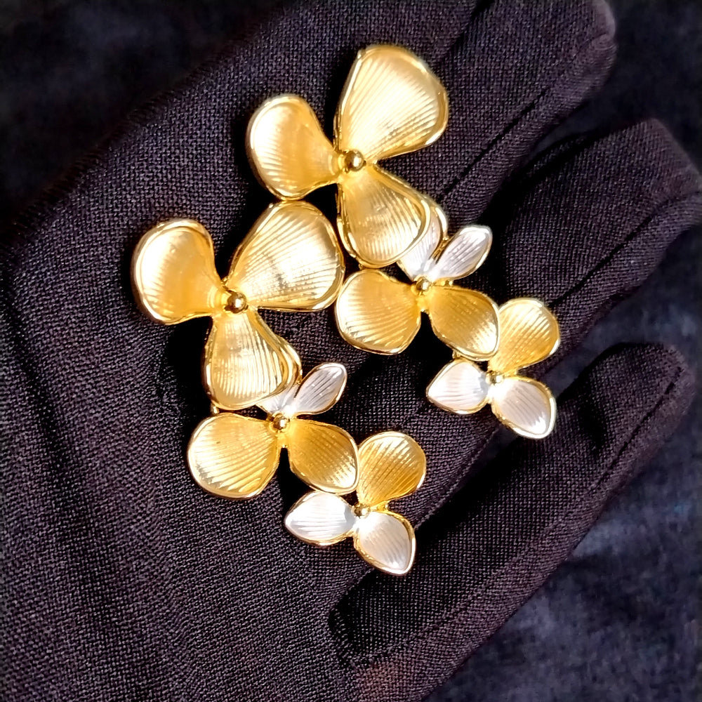 Gold and Silver Toned Floral Earrings Held by Black Gloved Hands