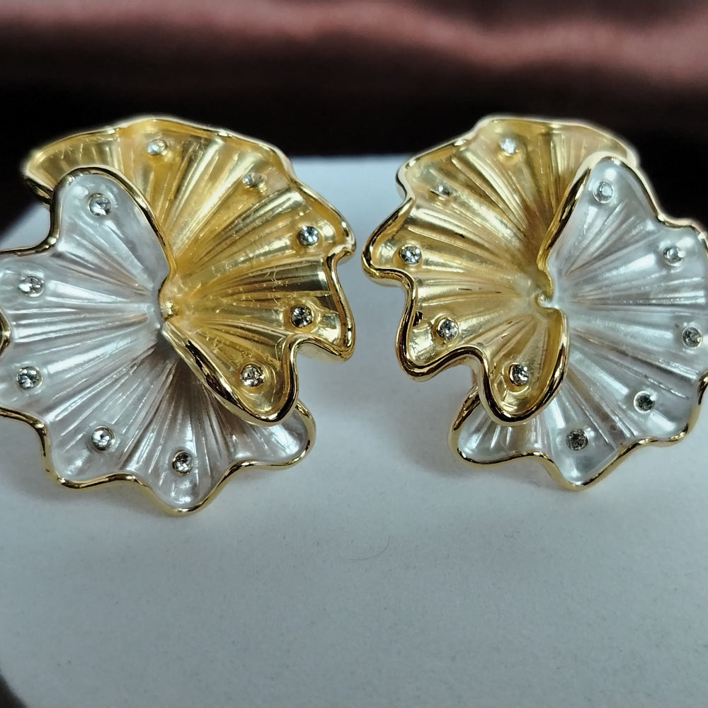 A Pair of Gold and Silver Toned Floral Earrings with Diamond Accents on White Surface and Brown Background
