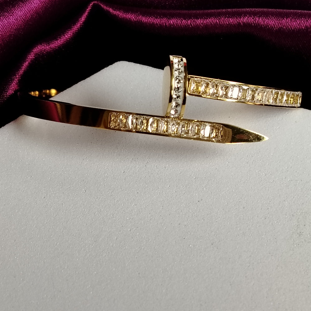 Golden Bracelet with American Diamond Embedded on a White Surface with Purple Fabric Background