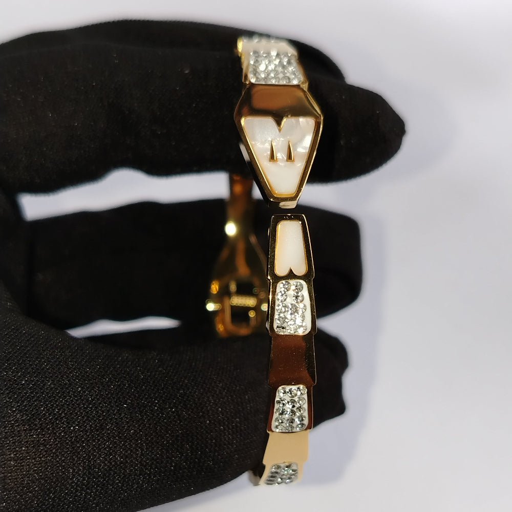Golden Snakehood Bracelet Held by Black Gloved Hand against White Background