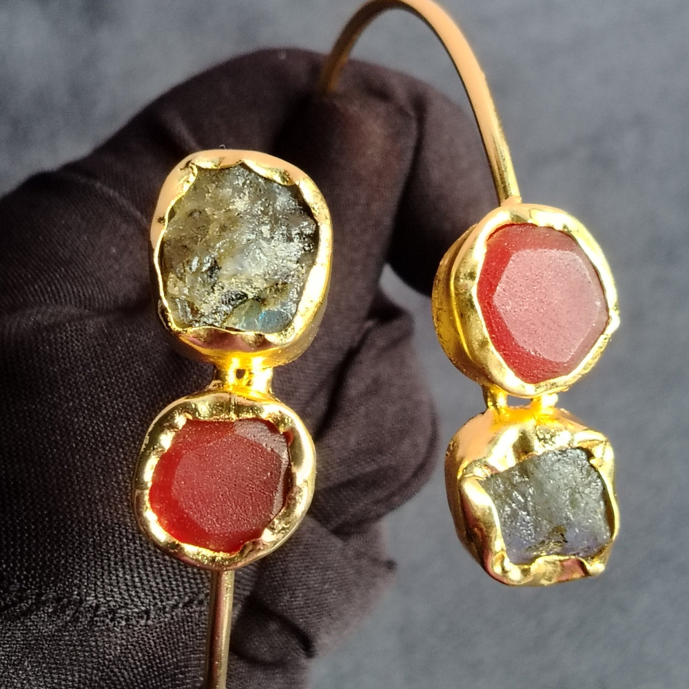 Golden Bracelet with Garnet and Black Onyx Gemstones Held by a Gloved hand against a Gray Background