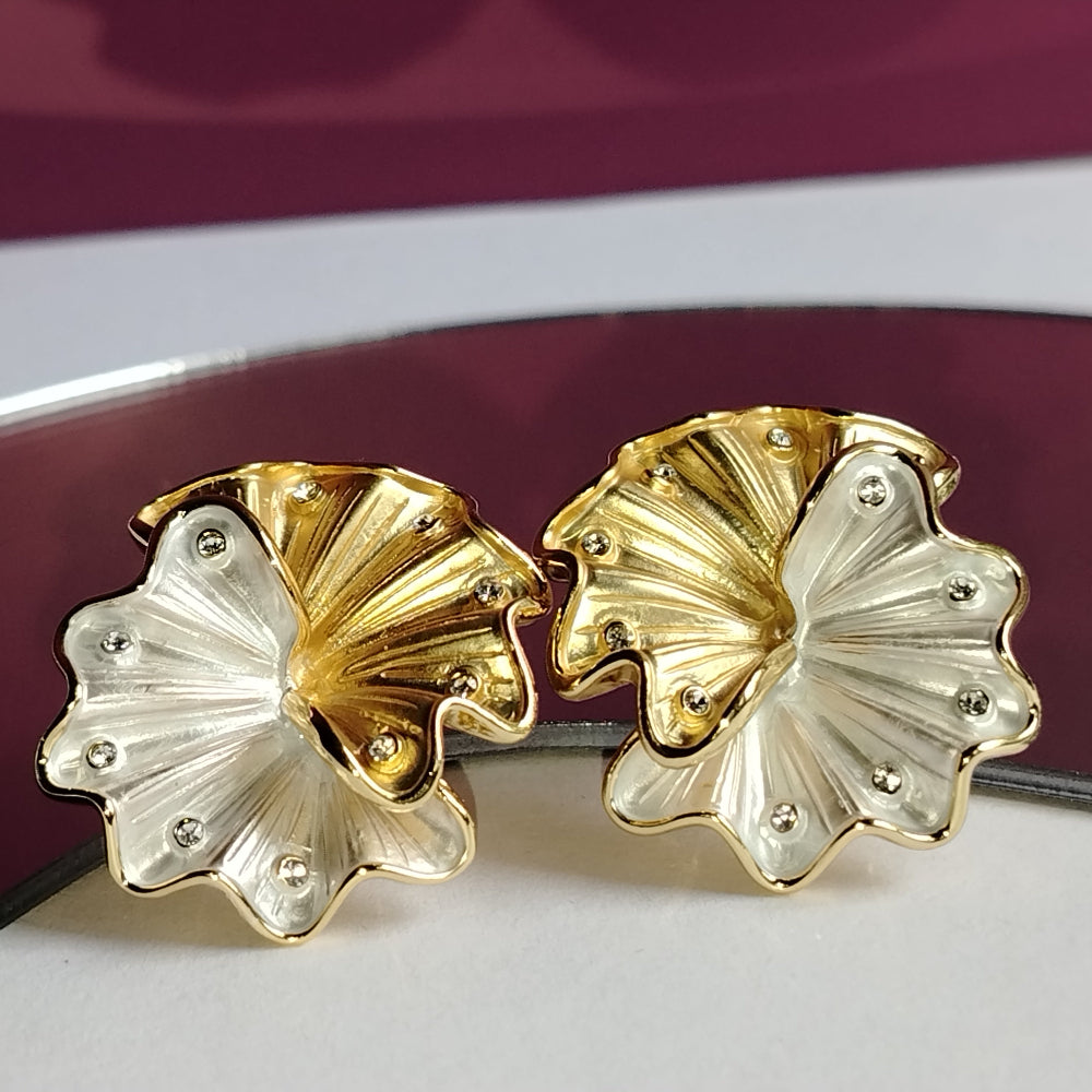 A pair of Gold and Silver Tone Floral Earrings with Diamond Accents on a White Surface with a Purple Background