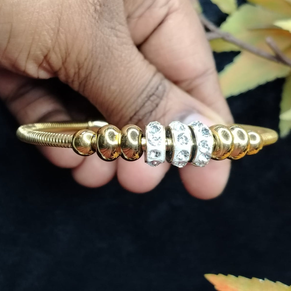 Golden Beads and Ad Loops Braclet Held by Hands on a Dark Background