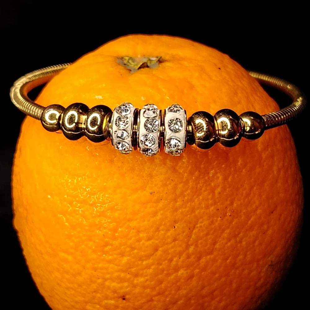 Golden Beads Braccelet with American Diamond Loops Kept on an Orange