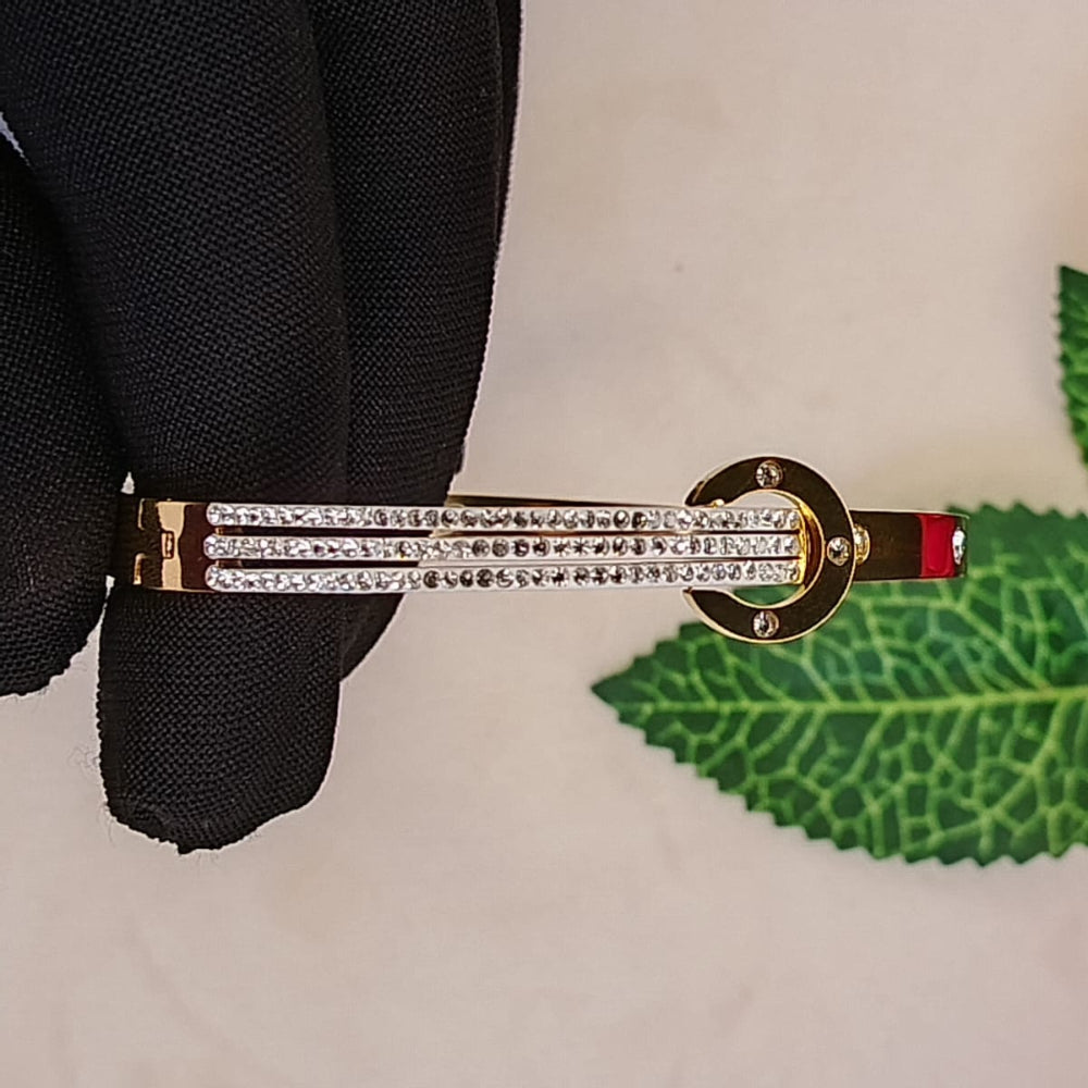 Golden Bracelet with Crystals on a White Background with Green Leaves
