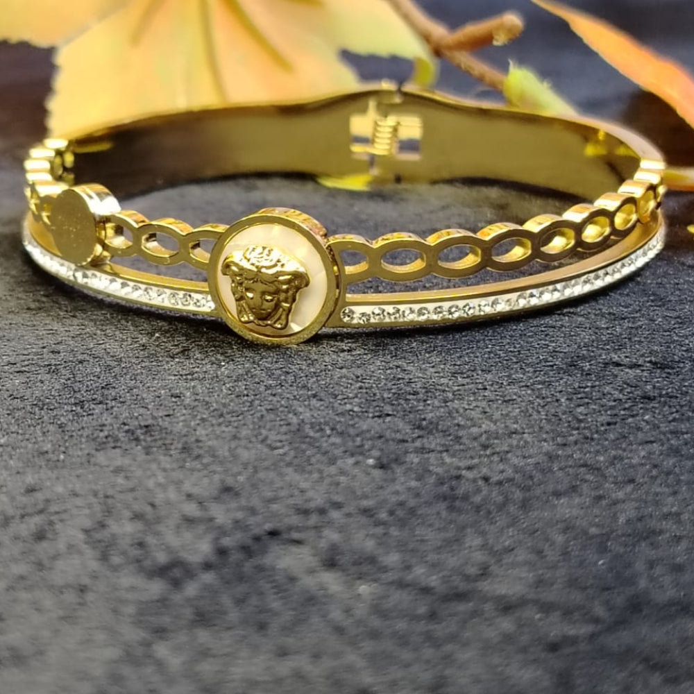 Gold bracelet with a Clear crystal and brand Logo on a dark background