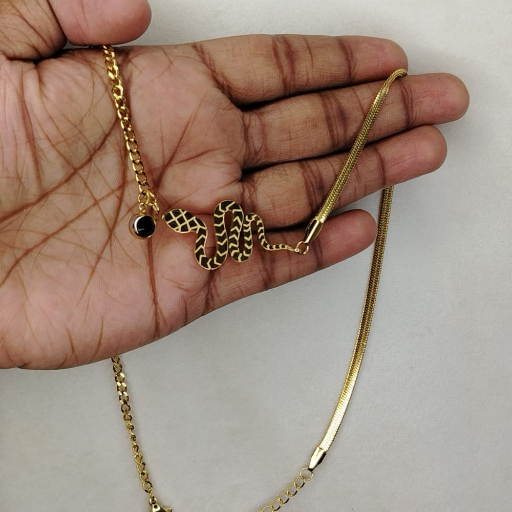 Golden Half and Half Snake Pendant Held in a Hand against a Plain Background