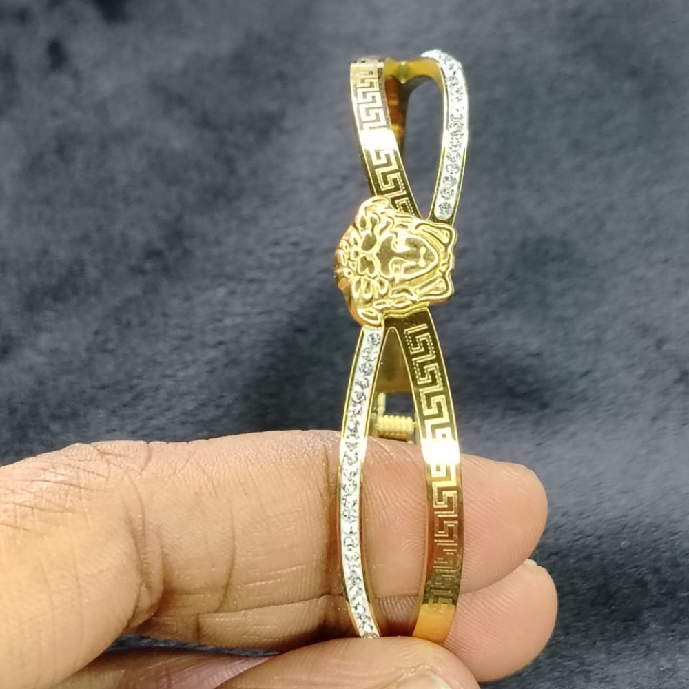 Golden Bracelet with Brand Logo in Twisted Design held by a hand against a dark Background