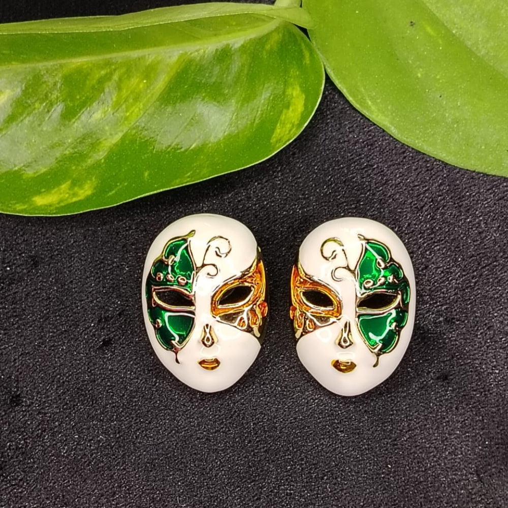 Pair of Mask-shaped Earrings with Green, Red, and Gold accents on a Dark surface with Leaves.