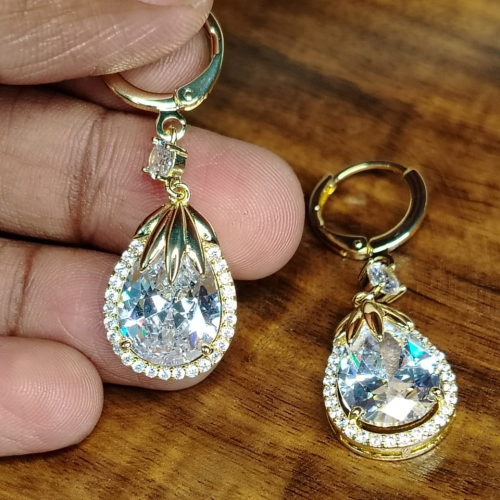 Golden American Diamond Tear Drop Hoops Held By Hands against Wooden Background