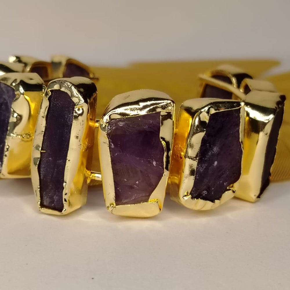 Gold-rimmed Amethyst Handcuff on A Beige Surface