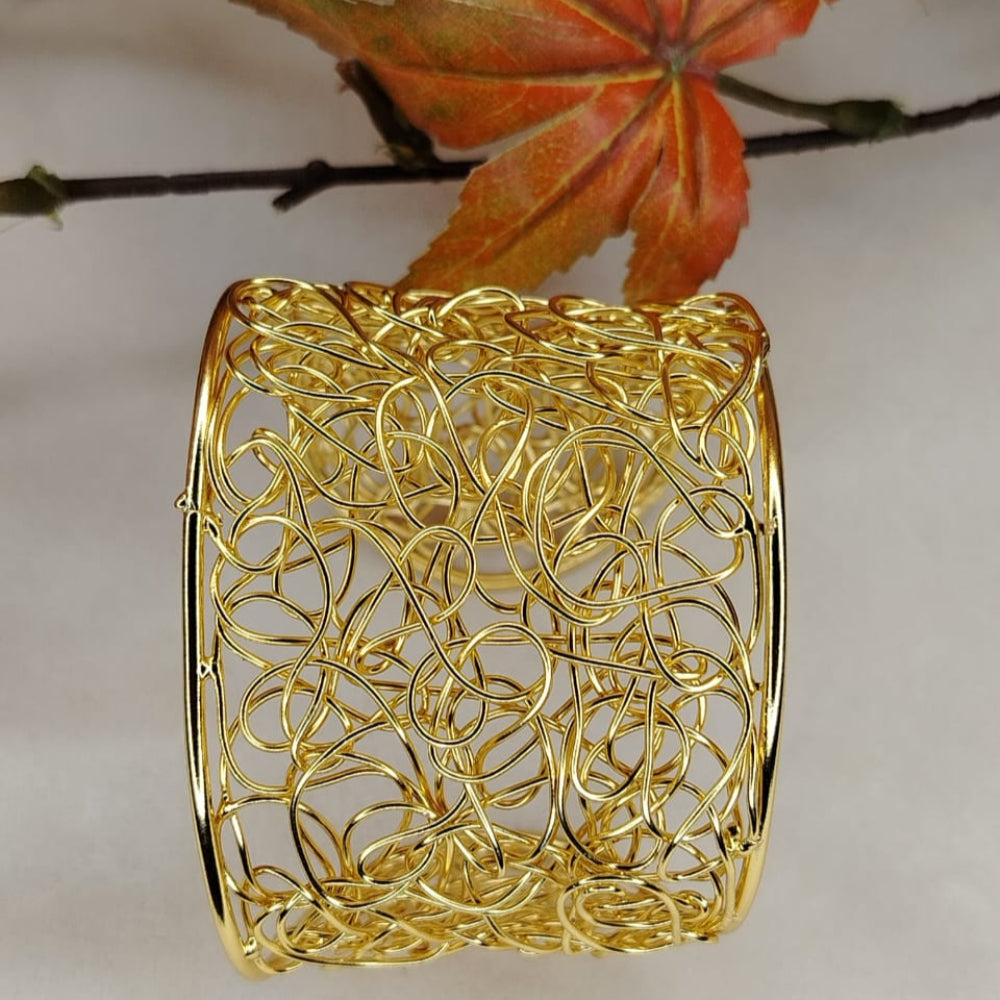 Gold Plated Filigree Handcuff or Barcelet on White Background and Leaves