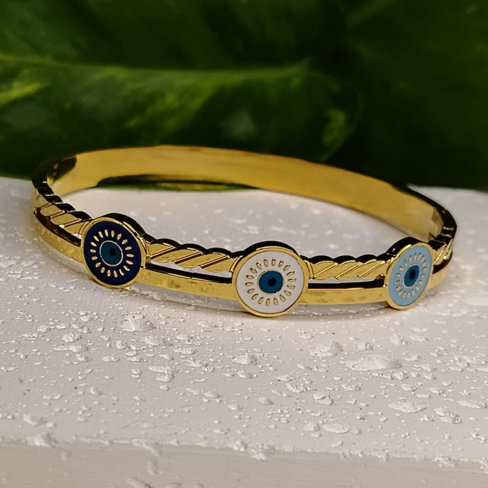 Golden Bracelet with 3 Evil Eyes on a WHite Surface with Leaves