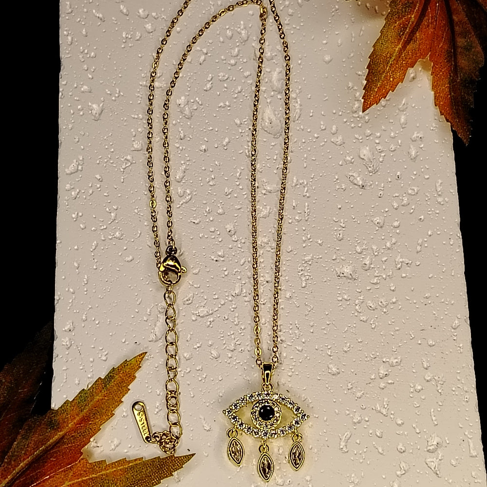 Golden Eye Pendant on a Textured White Surface with Autumn Leaves