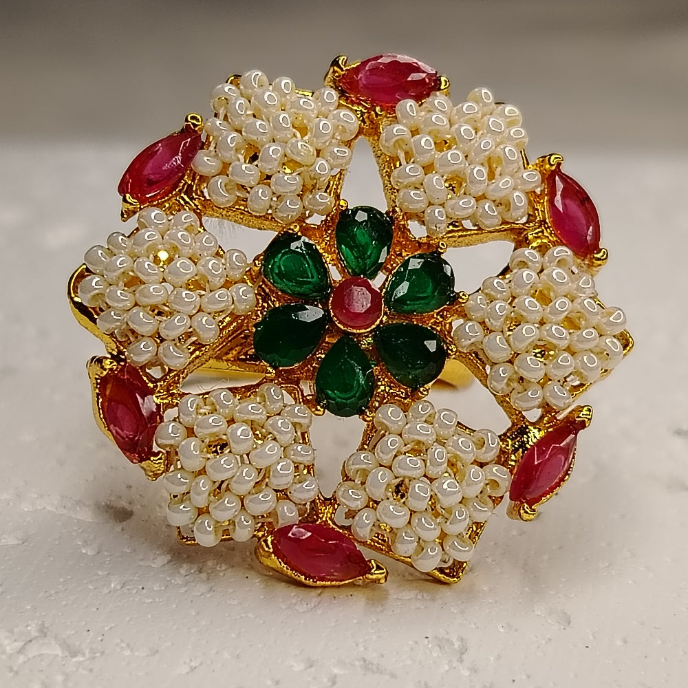 Decorative Ring with pearls, red and green gemstones on a neutral background