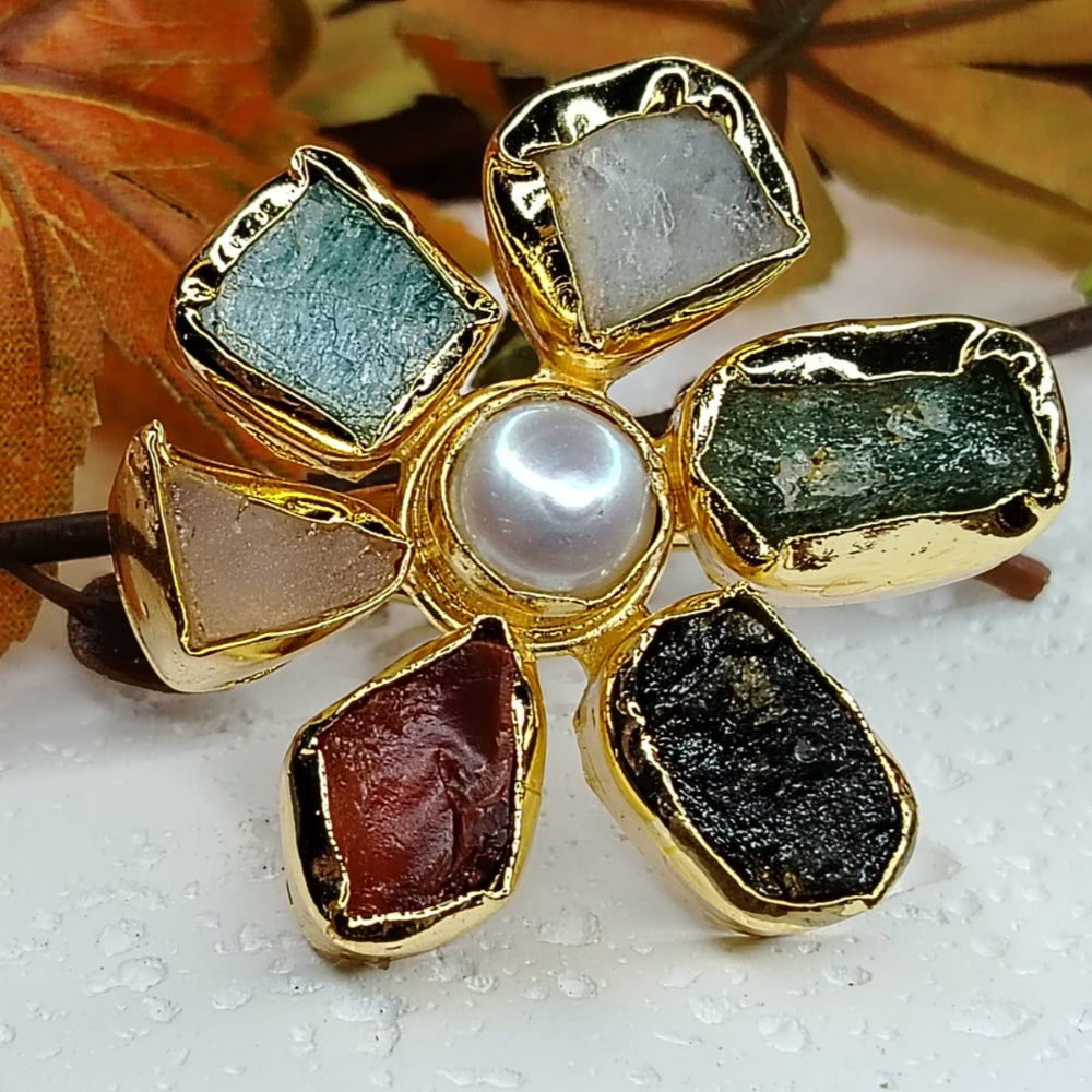 Golden Ring with Multicolored Natural Stones on White Surface with Autumn Leaves