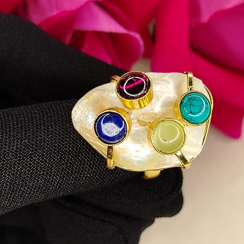 Golden pearl Ring with Multicolored Gem Stones Held by a Gloved Hand against Pink Flowers