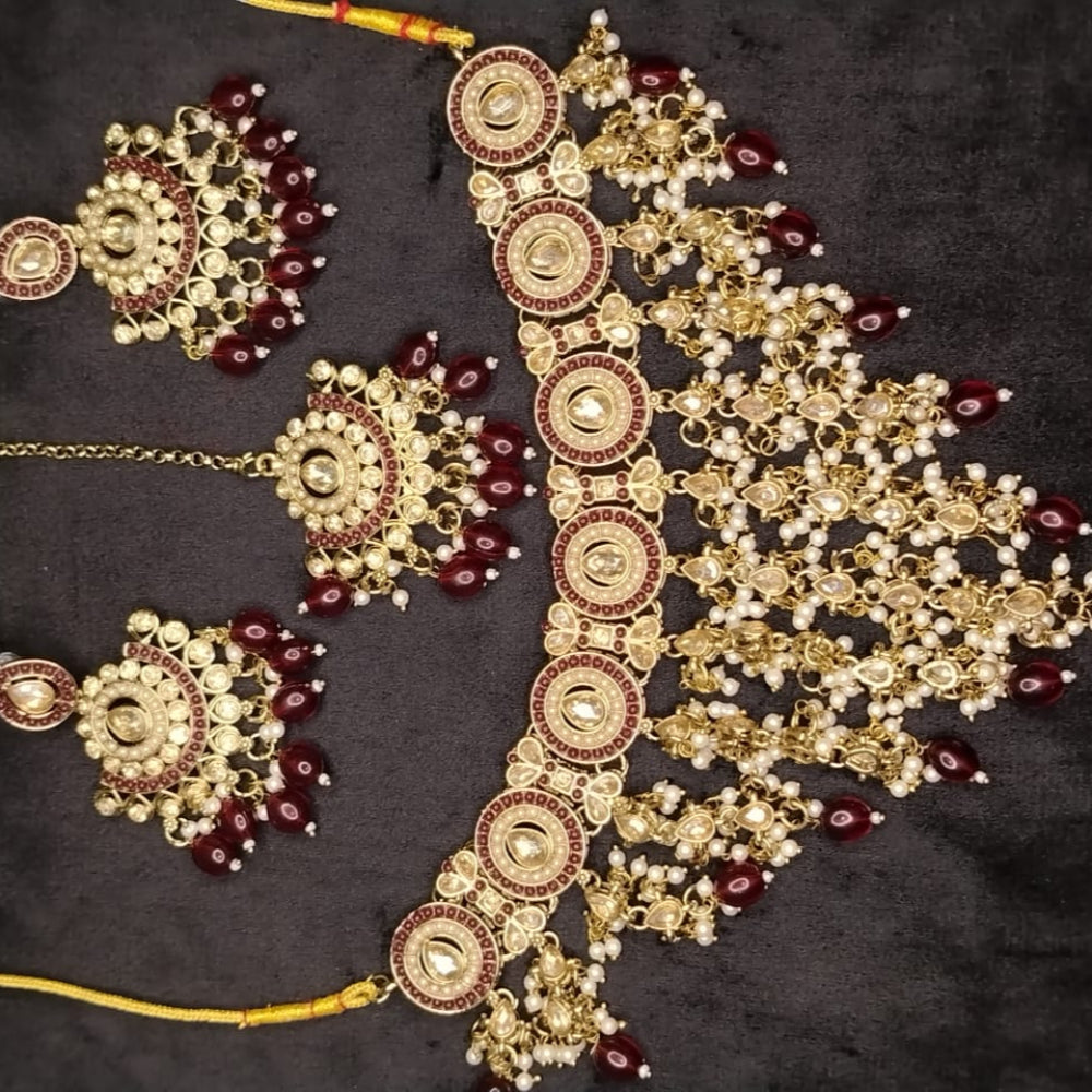 Ornate Golden Jewllery Set with Maroon Beads and Kundan on a Dark Surface