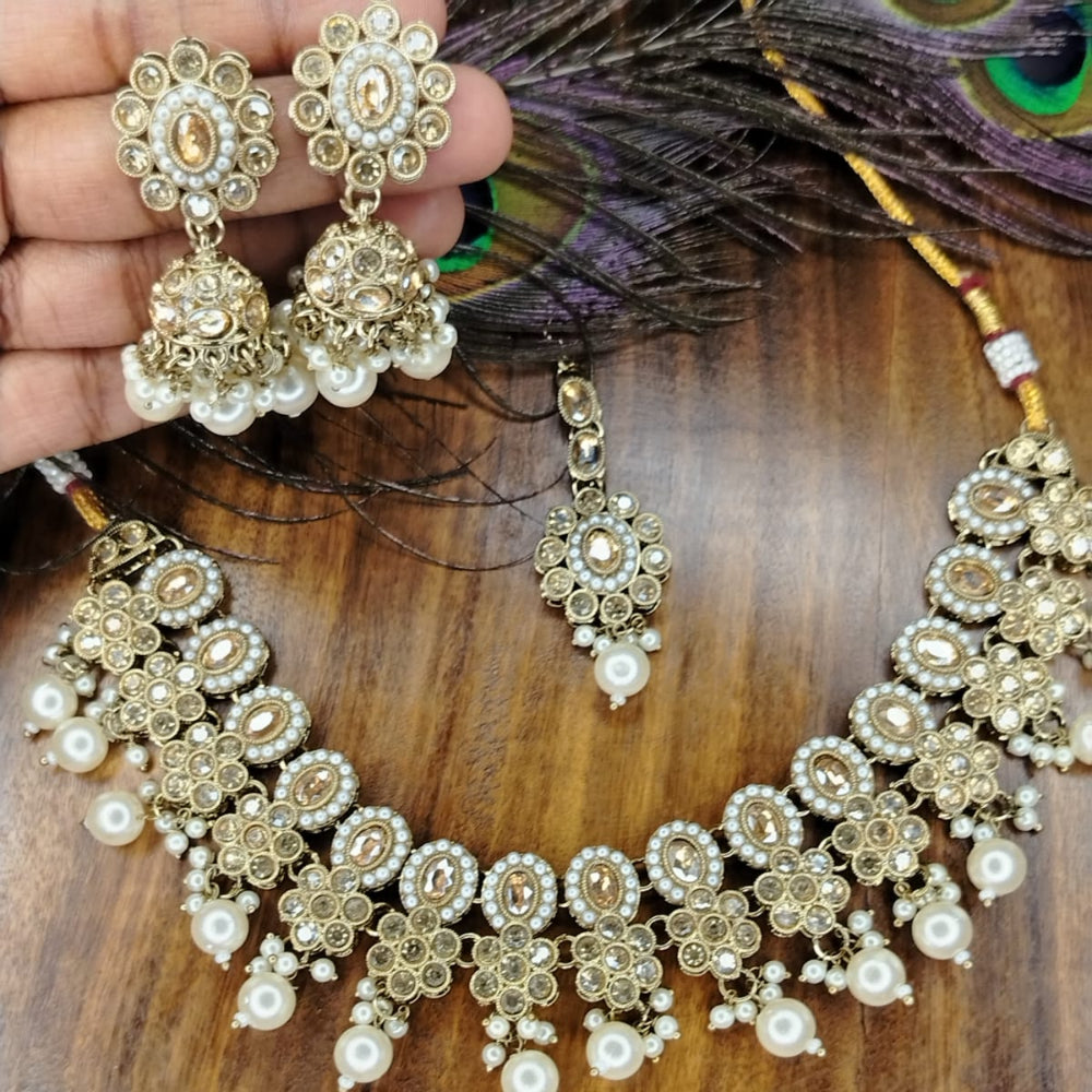 Golden Jewellery Set with Pearl and Kundan on Wooden Surface and Peacock Feather