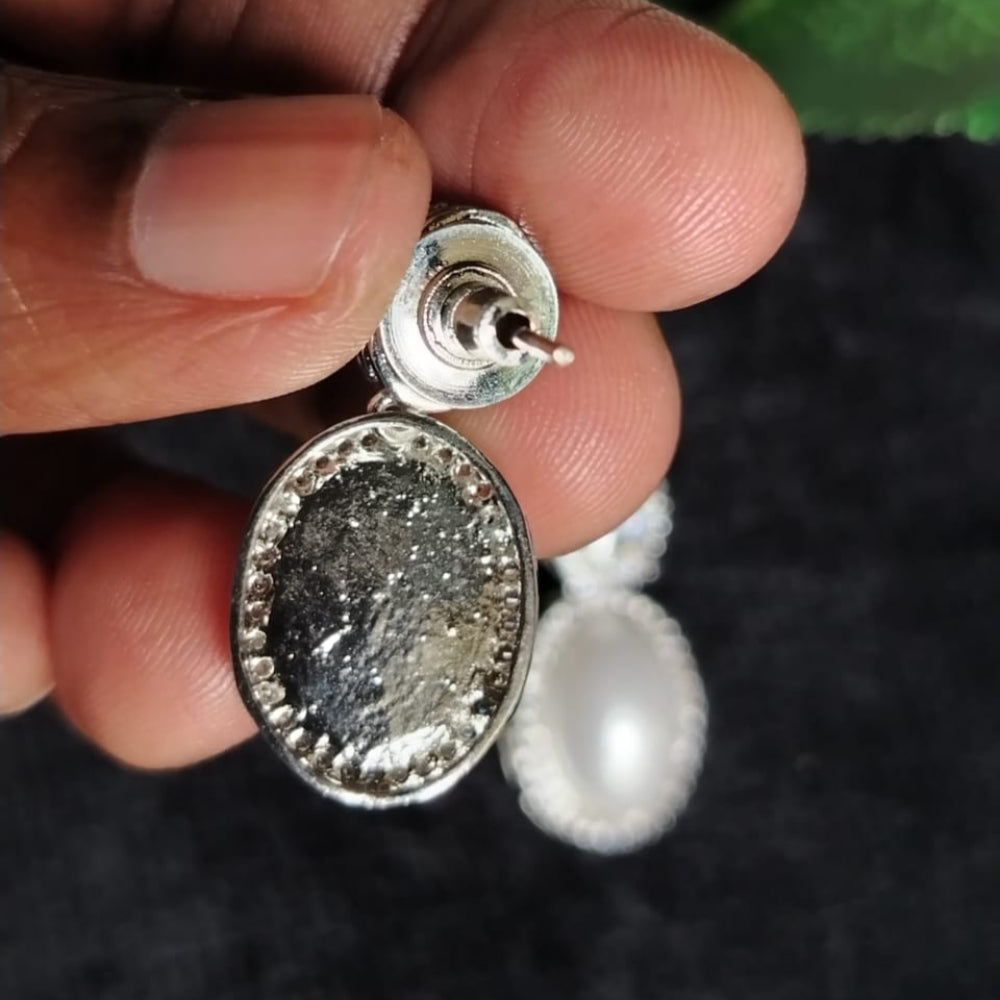 Silver Polishe Earrings held in hands against Black Surface