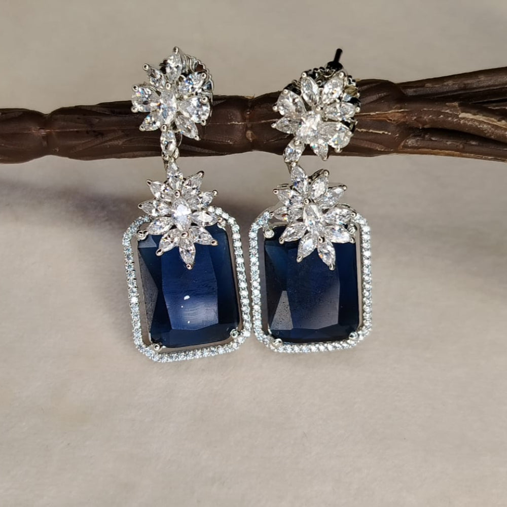 Pair of Diamond Replica Earrings with Blue Genstone on a White Surface hung on Branch
