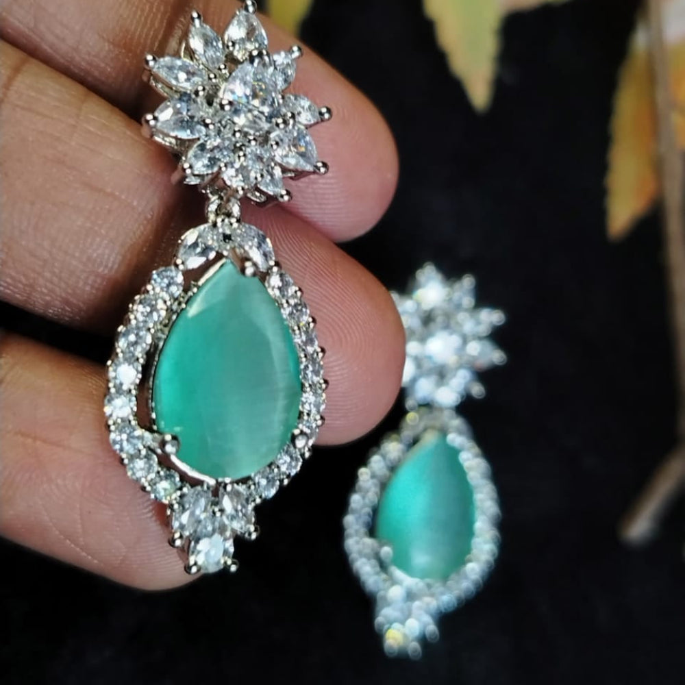 Mint Green Tear Drop Diamond Replica Earrings Held in Hands Aginst Black Background
