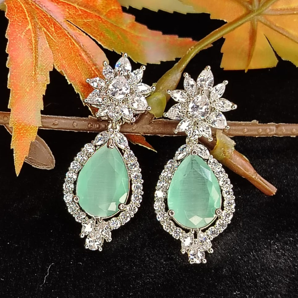 Starburst Earrings with Mint Tear Drop Diamond Accent Earrings on Black surface and Leaves