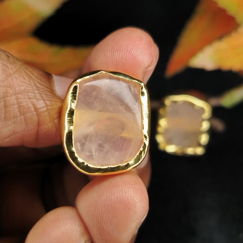 Gold-framed Rose Quartz Earrings held in Hands against Black surface