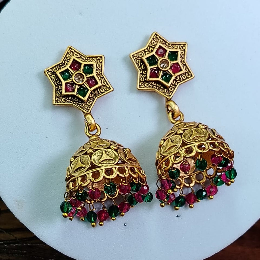 Golden Jhumka with green and red gemstones on a white plate