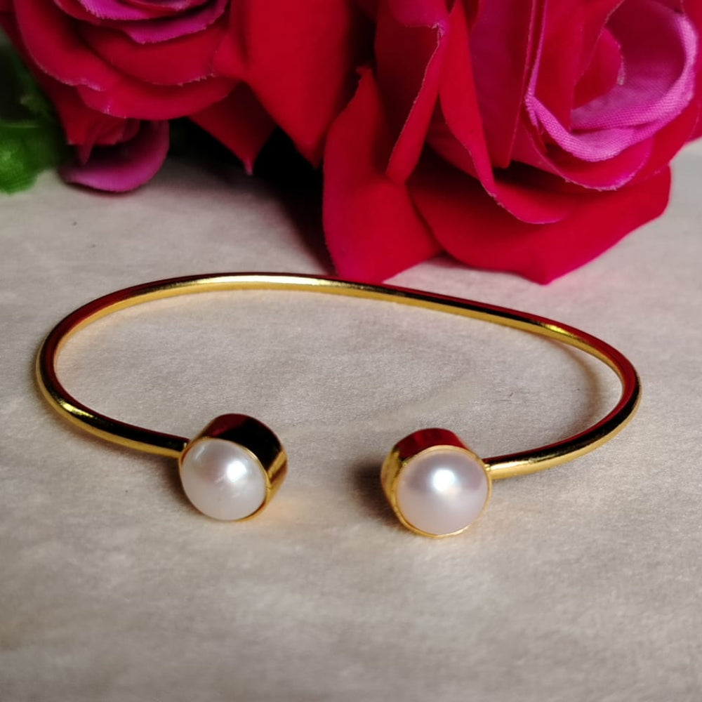 Golden bracelet with Pearls on a light background with pink flowers.