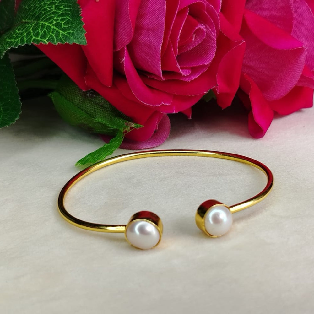 Golden bracelet with Natural Pearls in front of pink roses on a light background