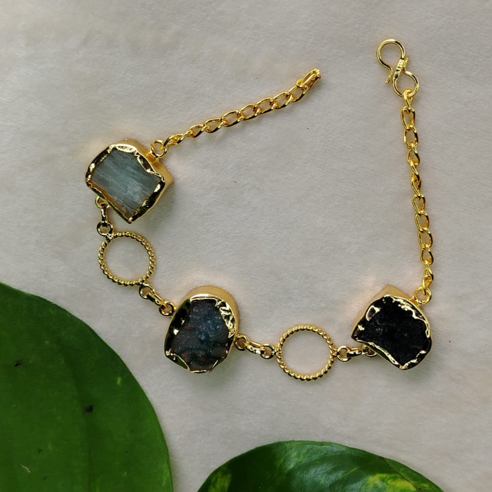 Gold bracelet with black stones on a light background