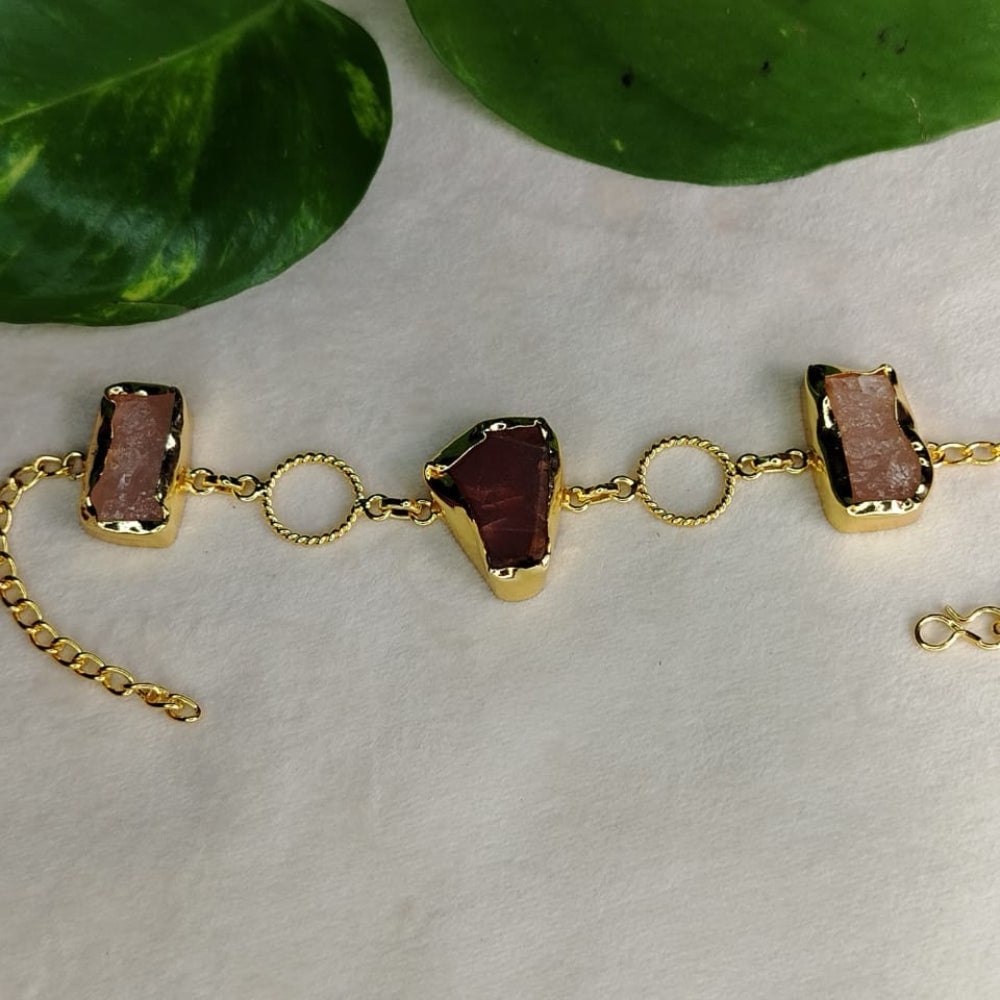 Gold bracelet with Maroon and Rose gemstones on a light background