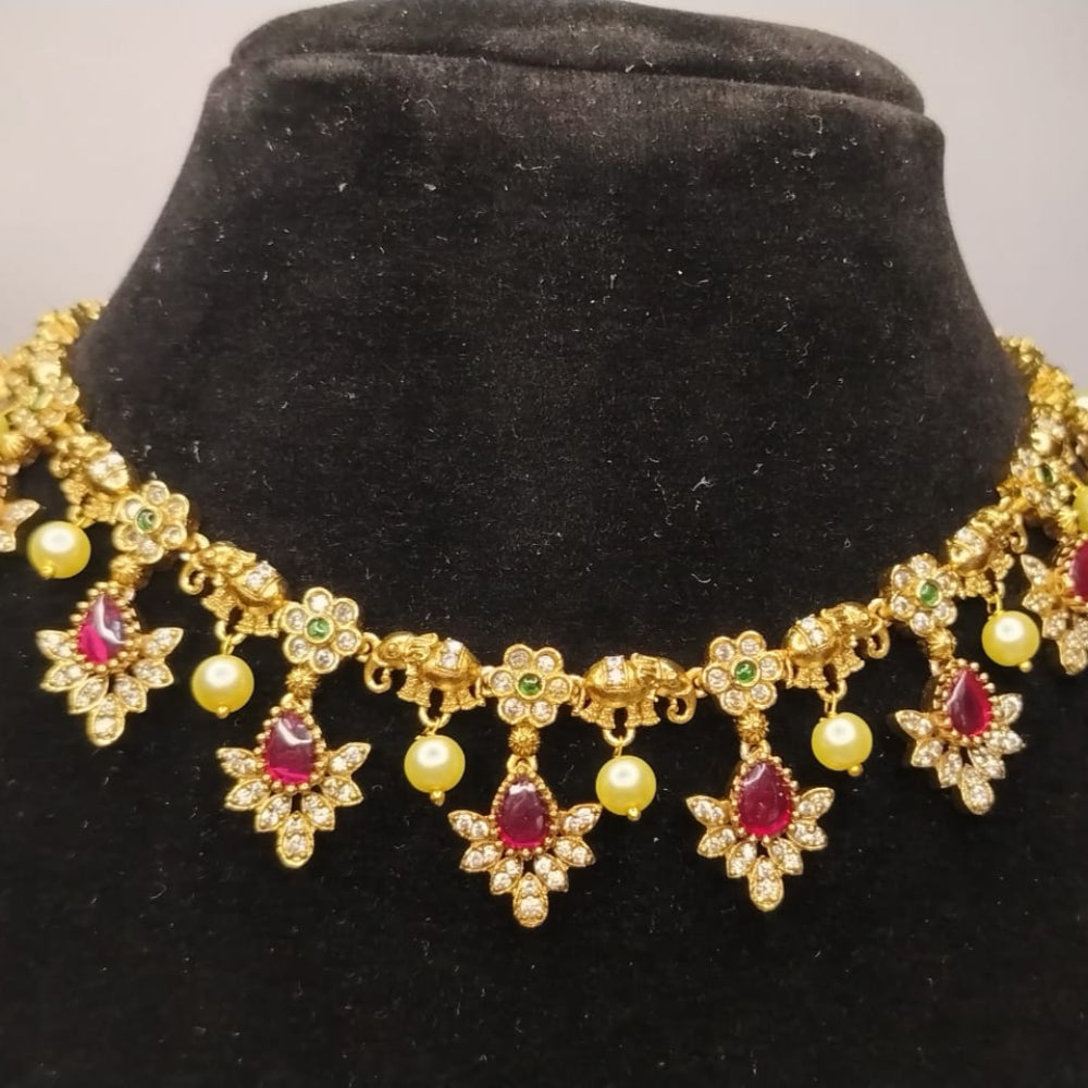 Gold necklace with red stones on a black velvet stand