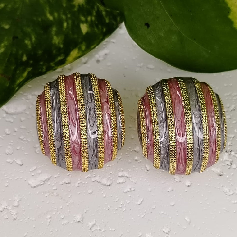 Pair of multicolored round earrings on a textured surface with green leaves in the background