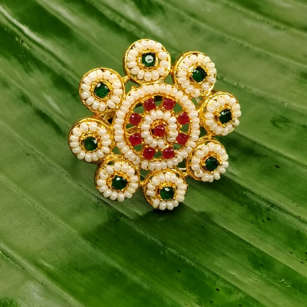 Decorative Ring with gold, green, and red elements on a green leaf background