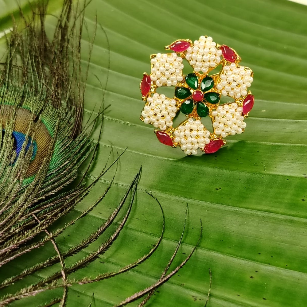 Decorative ring with pearls and gemstones on a green leaf