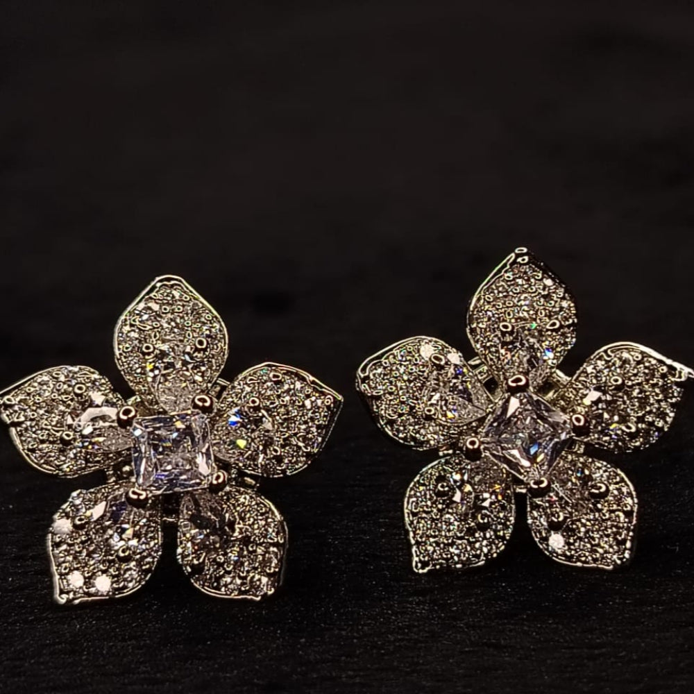 Flower-shaped silver earrings with clear gemstones on a black background