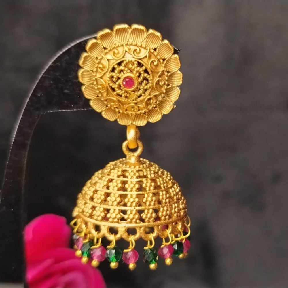 Golden jhumka earring with red and green beads on a dark background