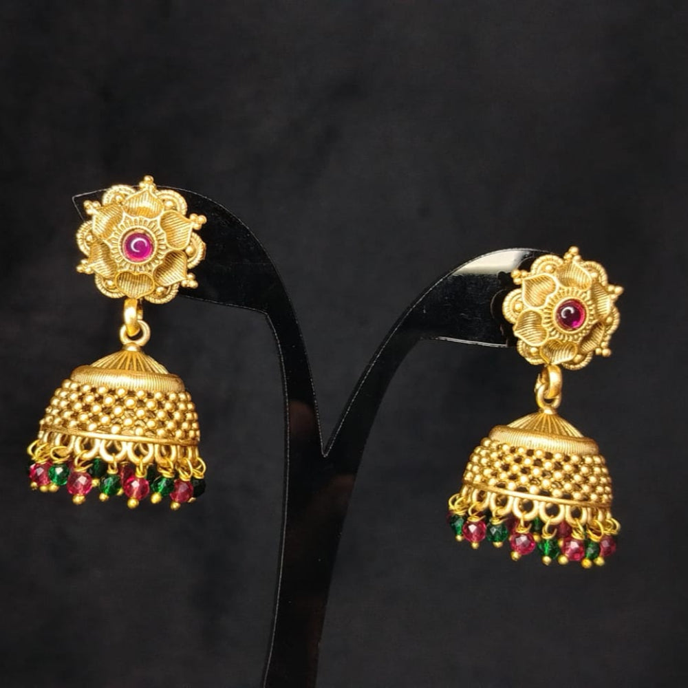 Golden Jhumka with red and green gemstones on a black background