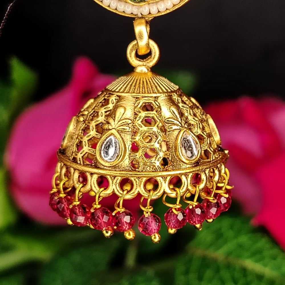 Golden jhumka earring with Kundan Stone and Pink Beads on a background with pink flowers