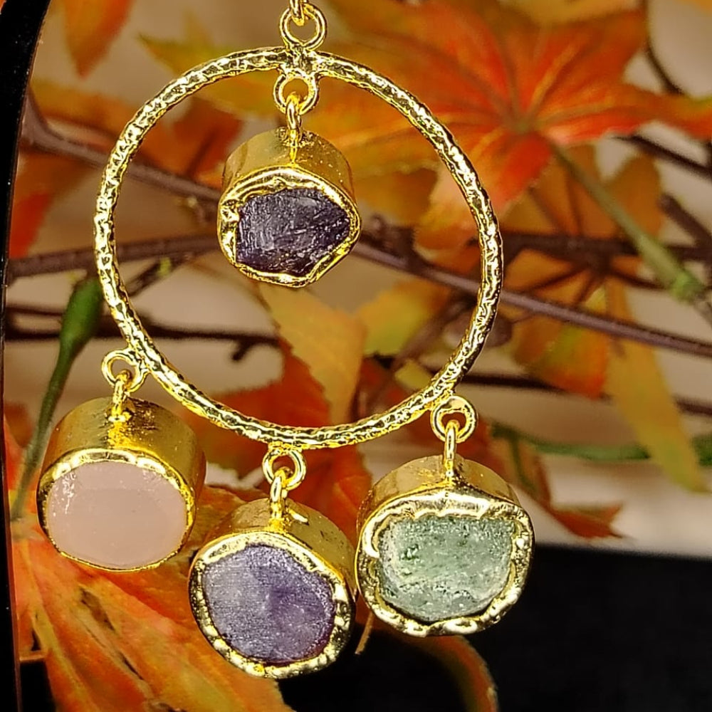 Gold-framed earrings with gemstones against a floral background