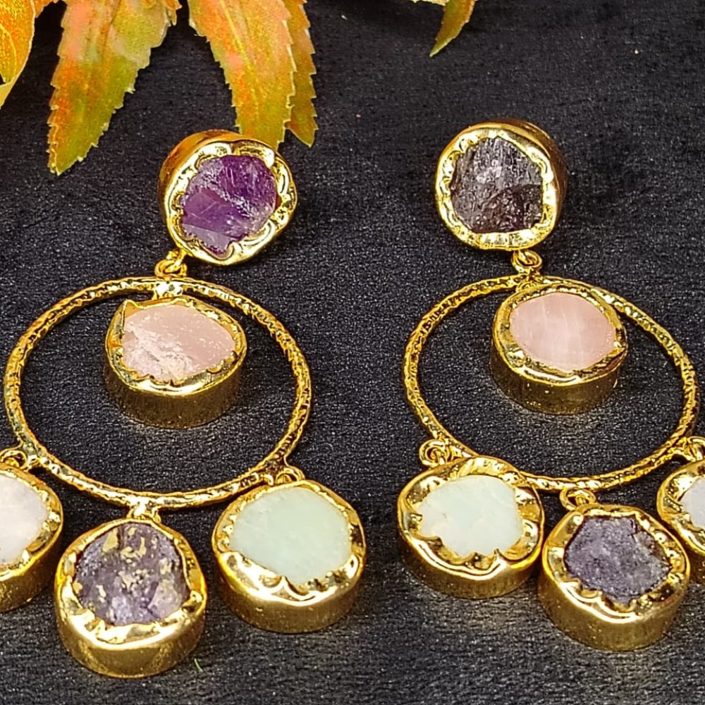Pair of golden earrings with colorful Natural gemstones on a dark surface.