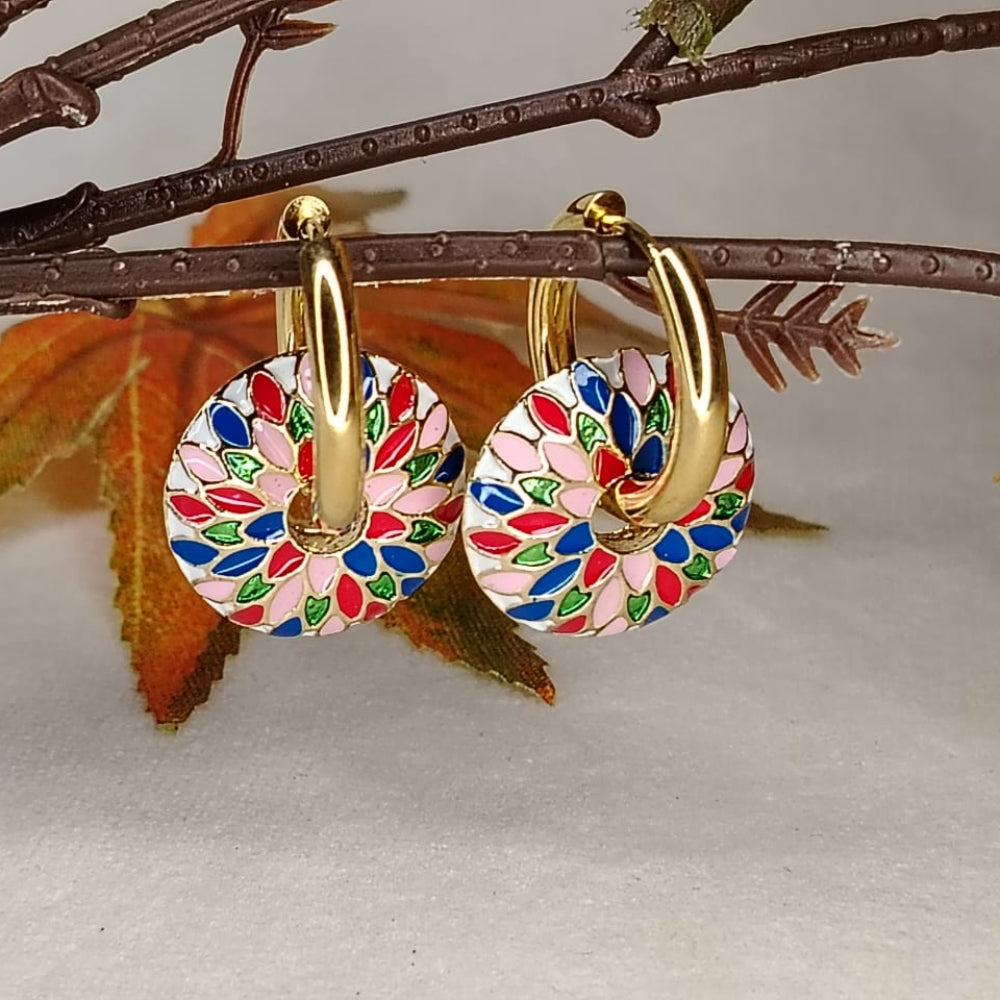 Colorful hoop earrings with gold accents on a branch with leaves.