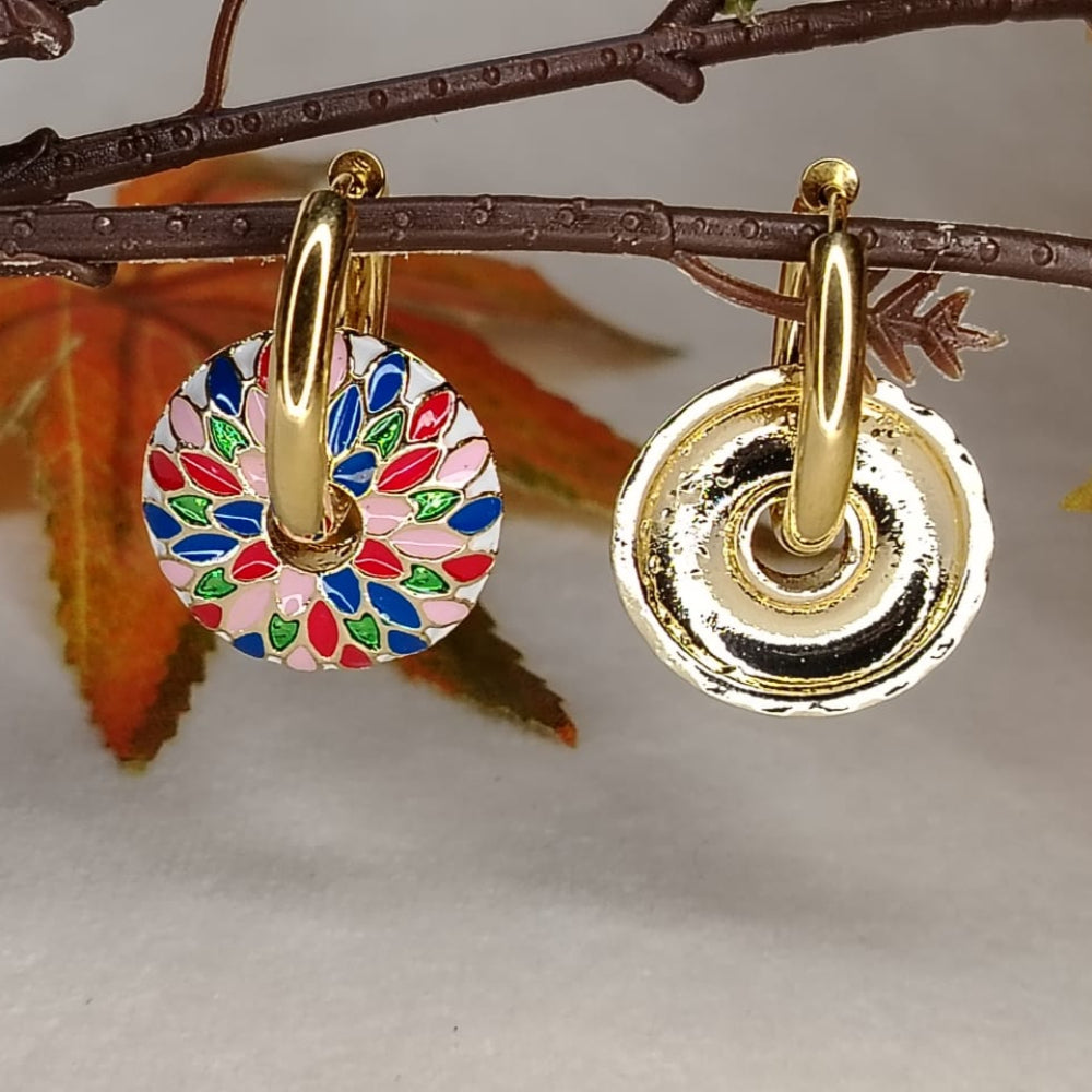 Gold earrings with colorful circular design on a branch with leaves